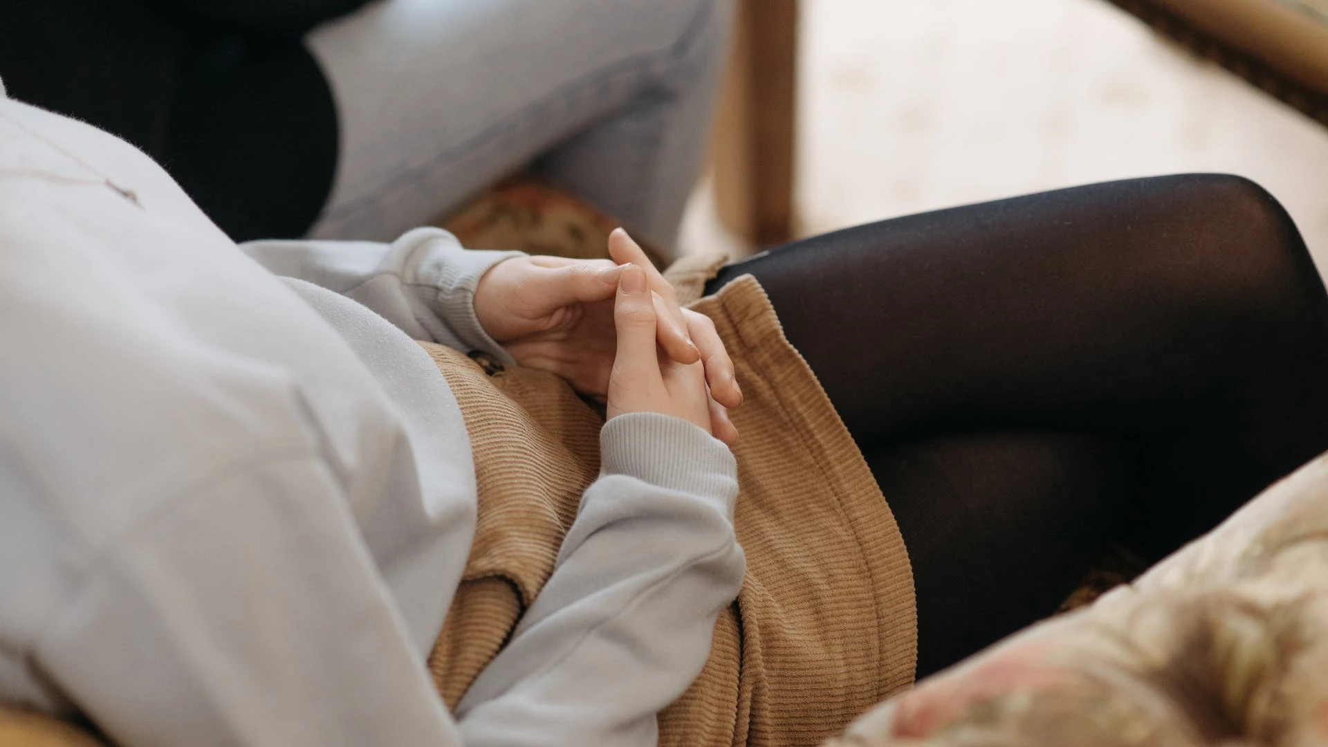 Kobieta siedząca na kanapie ze skrzyżowanymi dłońmi